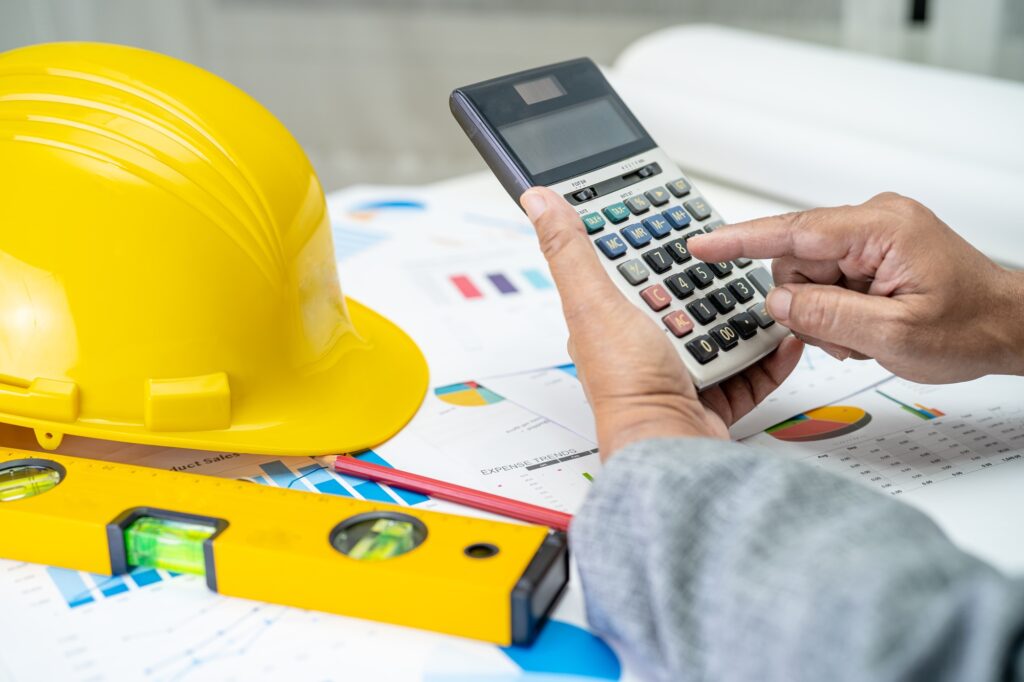 Architect or engineer working project accounting with graph and construction helmet in office.